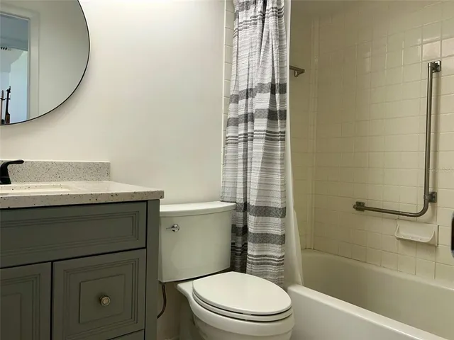 a bathroom with a granite countertop toilet sink and mirror