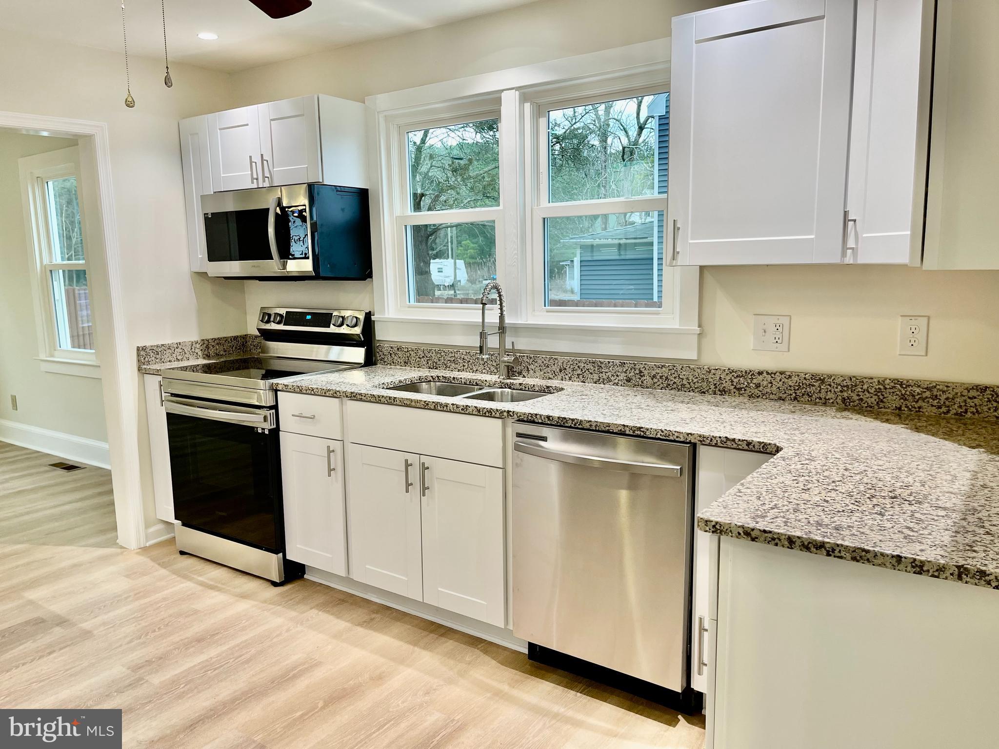 26540 Deal Island Road Princess Anne, MD 21853 - Photo 10 of 76 a kitchen with granite countertop a sink and a stove top oven with wooden floor