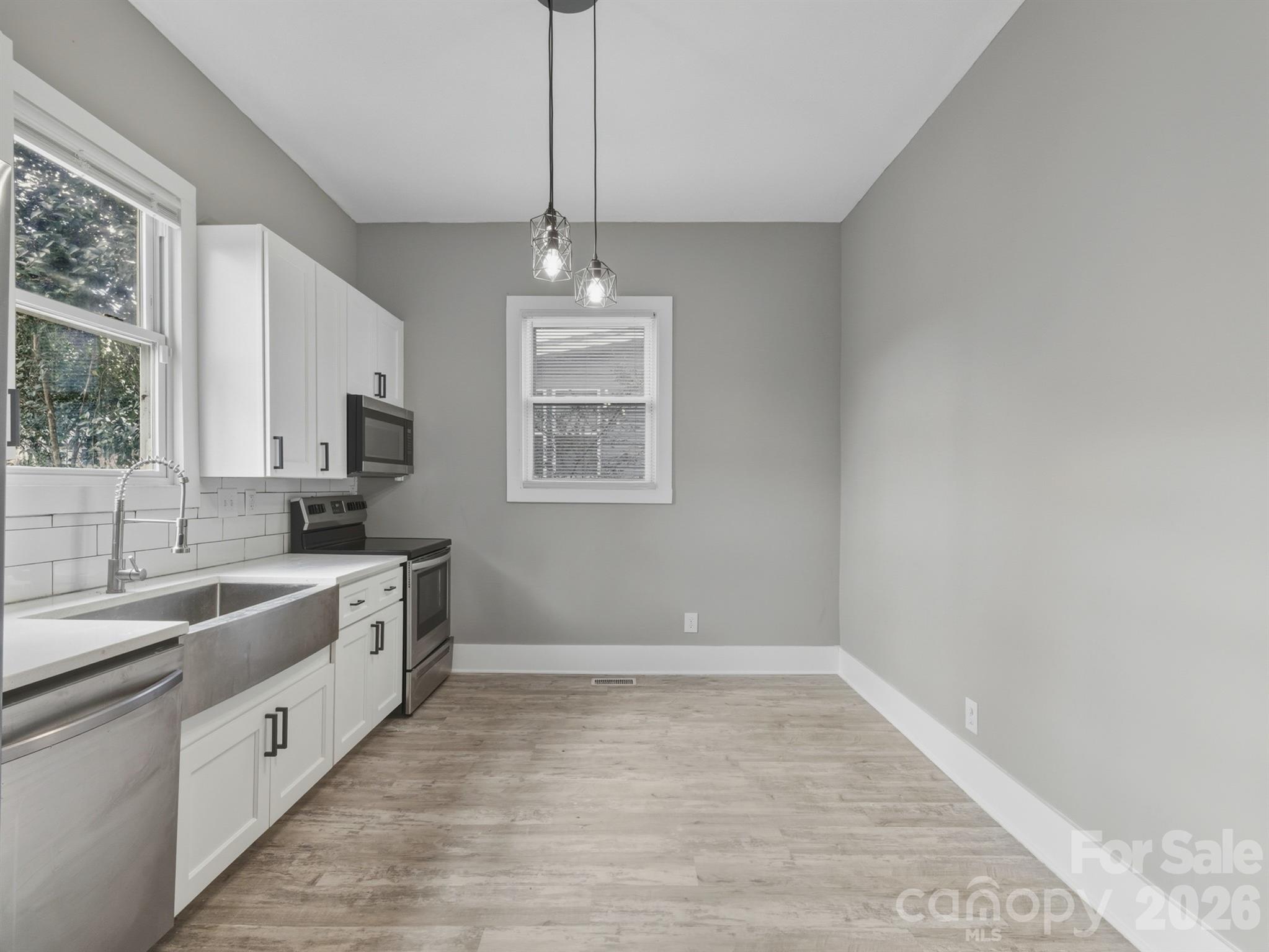 4313 Hovis Road Charlotte, NC 28208 - Photo 6 of 24 a large white kitchen with granite countertop a sink dishwasher a stove and white cabinets with wooden floor