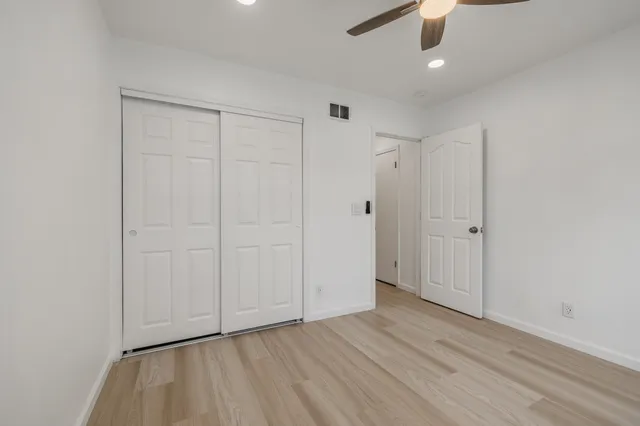 an empty room with wooden floor cabinet and windows