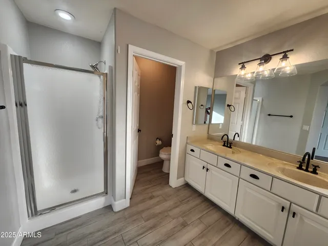 a bathroom with a double vanity sink a toilet a mirror and bathtub
