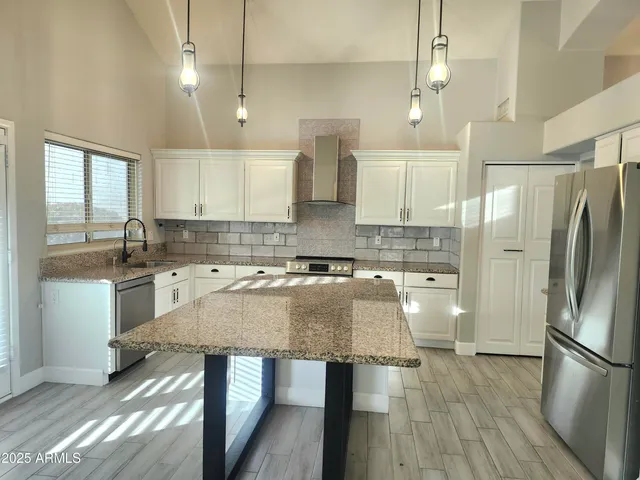 a kitchen with stainless steel appliances granite countertop a sink refrigerator and cabinets