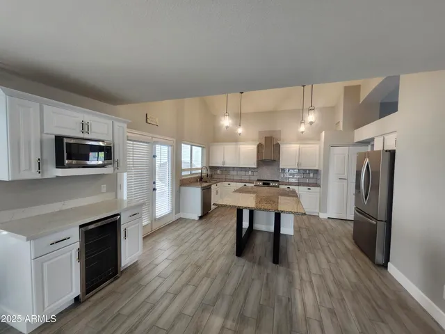 a kitchen with stainless steel appliances a microwave a stove a sink dishwasher a refrigerator white cabinets and wooden floor