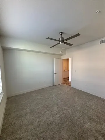 an empty room with a ceiling fan and window