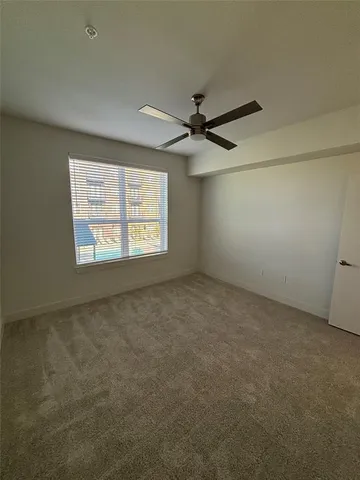 an empty room with a window and a fan