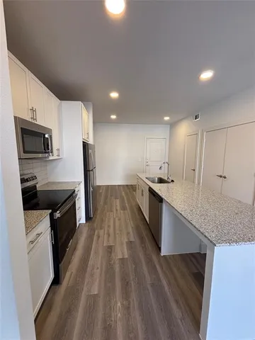 a large kitchen with a center island wooden floor stainless steel appliances and cabinets