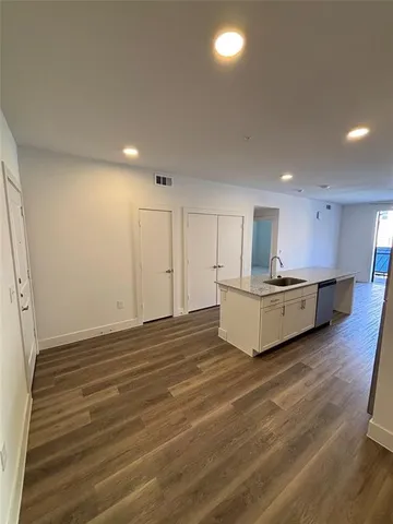a view of kitchen and empty room with wooden floor
