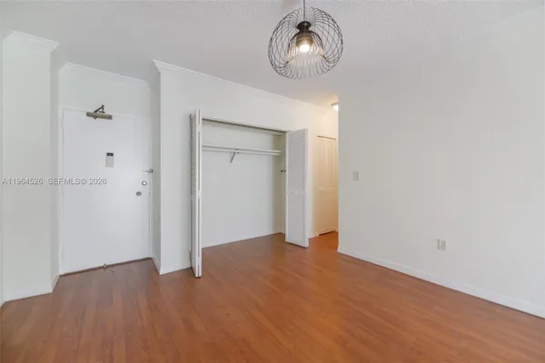 a view of an empty room with wooden floor and closet