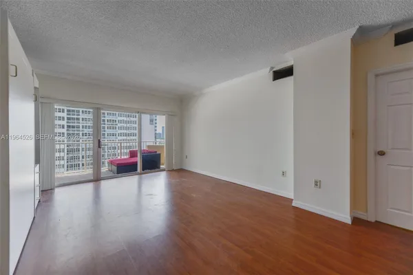 a view of empty room with wooden floor and window