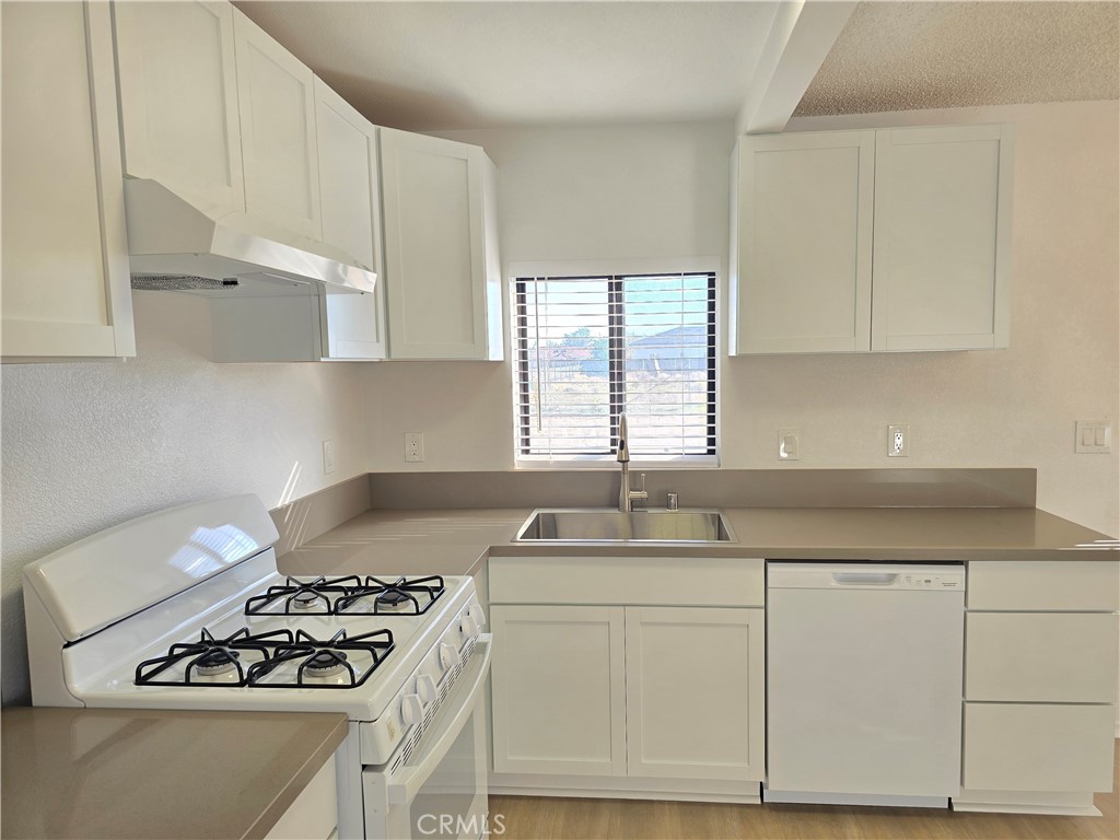 8249 Catalpa Avenue, Unit A California City, CA 93505 - Photo 3 of 12 a kitchen with granite countertop white cabinets and white appliances