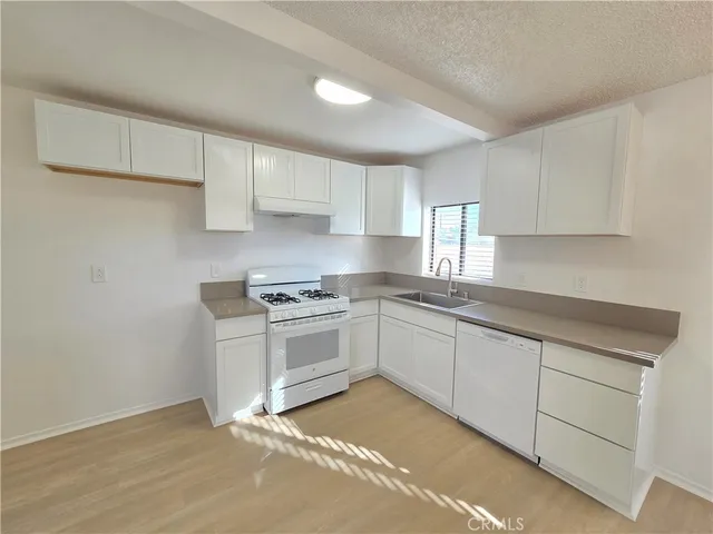 a kitchen with granite countertop white cabinets and white appliances