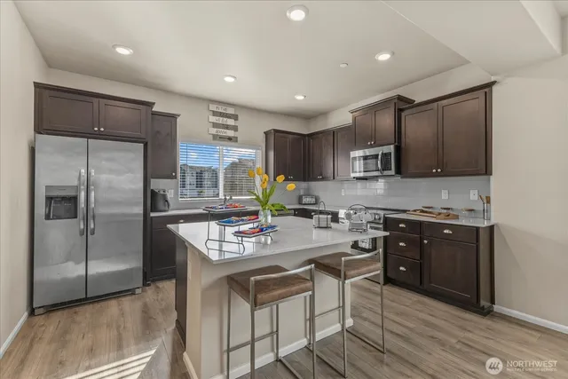 a kitchen with stainless steel appliances granite countertop a refrigerator stove microwave and cabinets