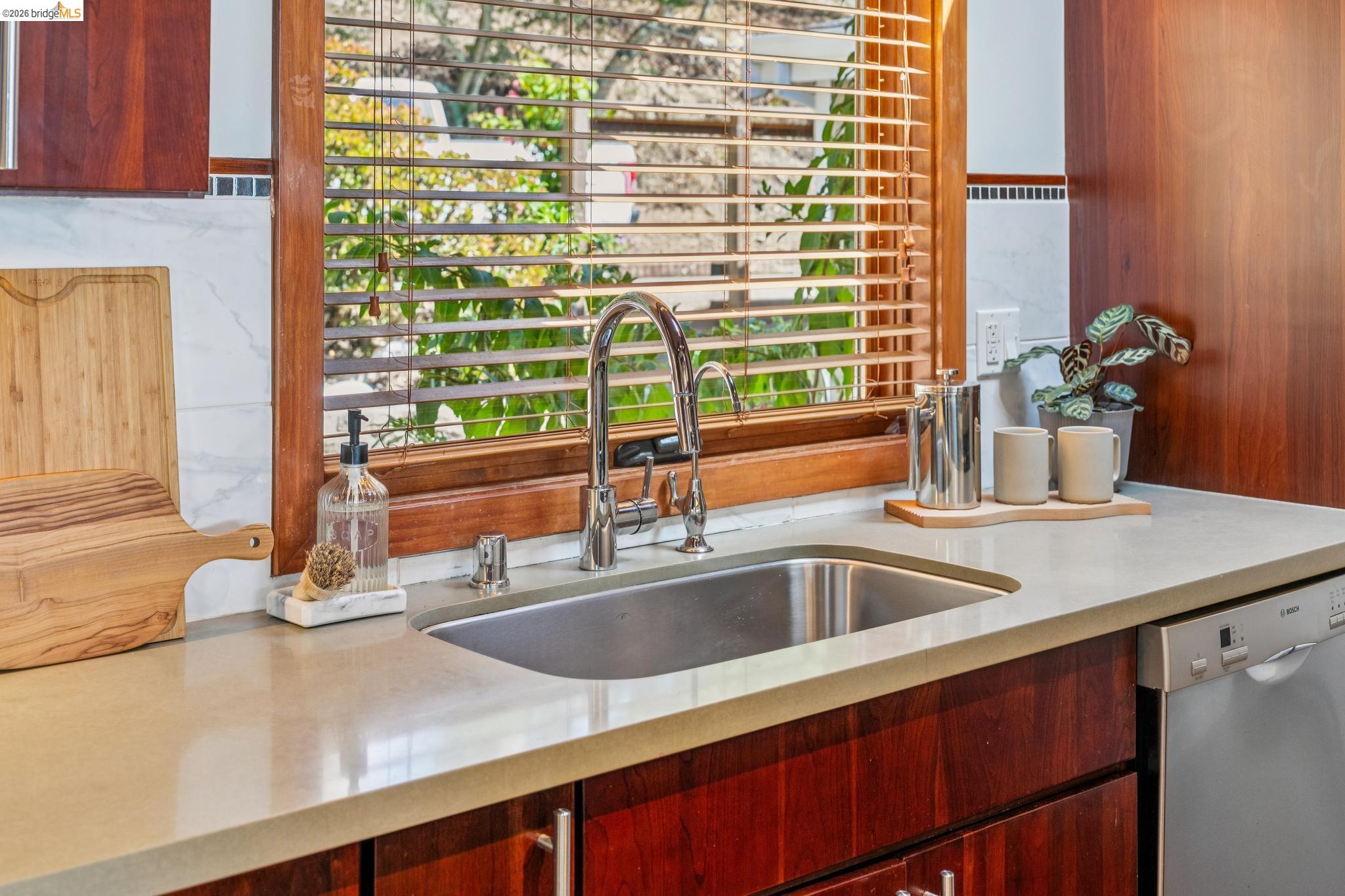 1394 Queens Road Berkeley, CA 94708 - Photo 13 of 63 Stainless steel sink with a gooseneck faucet, light-toned countertops, wood cabinetry, and a dishwasher
