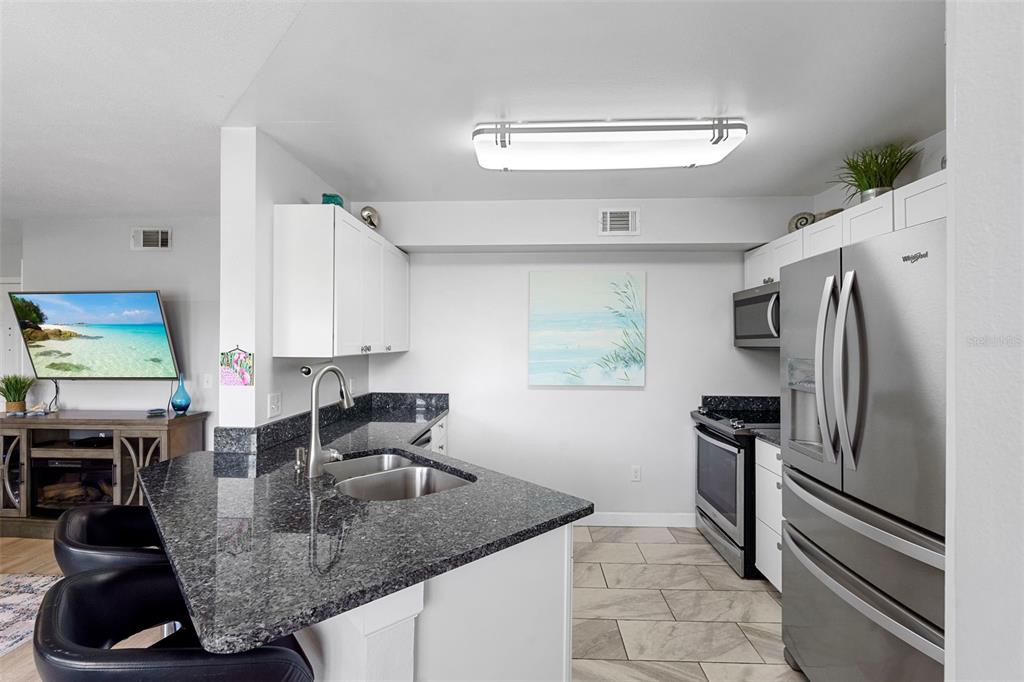 7470 Highway 1, Unit 105 Cocoa, FL 32927 - Photo 16 of 37 a kitchen with stainless steel appliances granite countertop a sink refrigerator and microwave