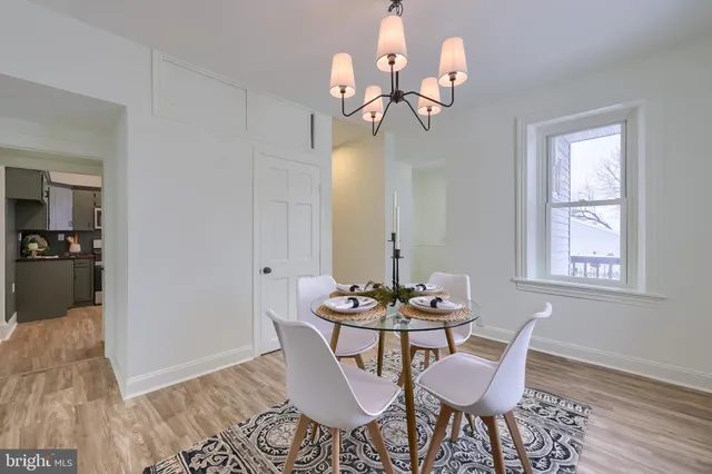 a dining room with wooden floor a chandelier a glass table and chairs