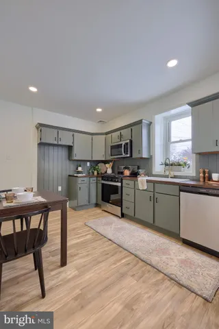a kitchen with stainless steel appliances kitchen island granite countertop a refrigerator a stove a sink dishwasher and white cabinets with wooden floor
