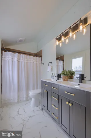 a spacious bathroom with a double vanity sink toilet and a mirror