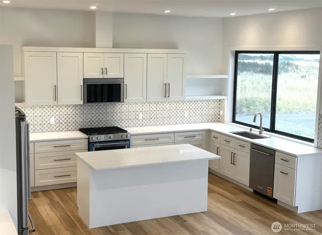 a kitchen with granite countertop white cabinets and black appliances