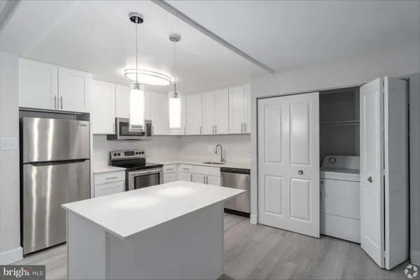 a kitchen with stainless steel appliances a refrigerator a stove a sink and white cabinets