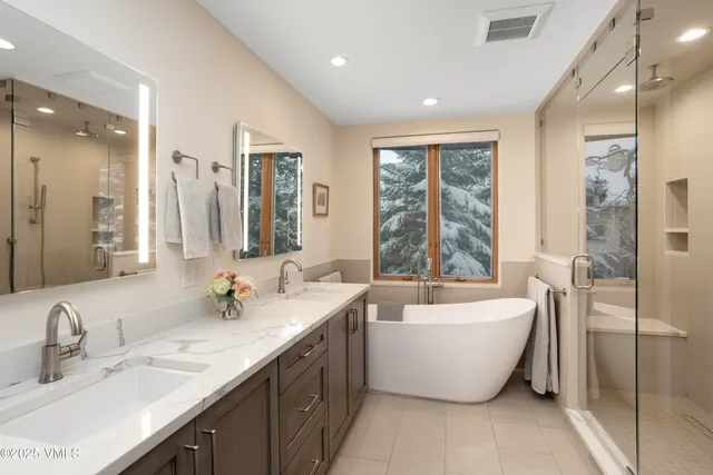 a spacious bathroom with a double vanity sink large mirror and a bathtub