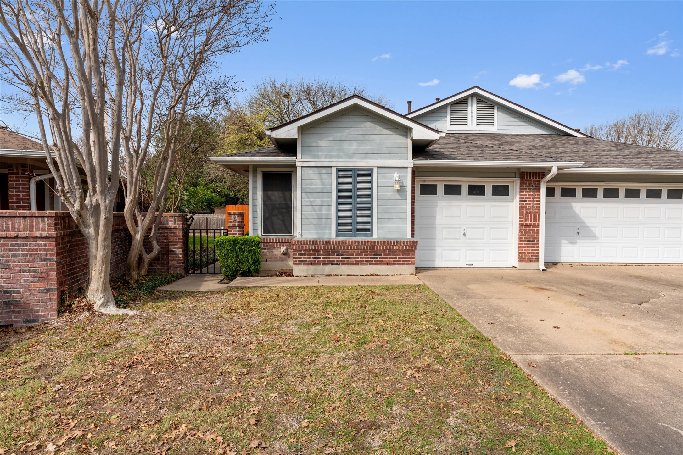 Ranch-style home with concrete driveway, a garage, roof with shingles, and brick siding