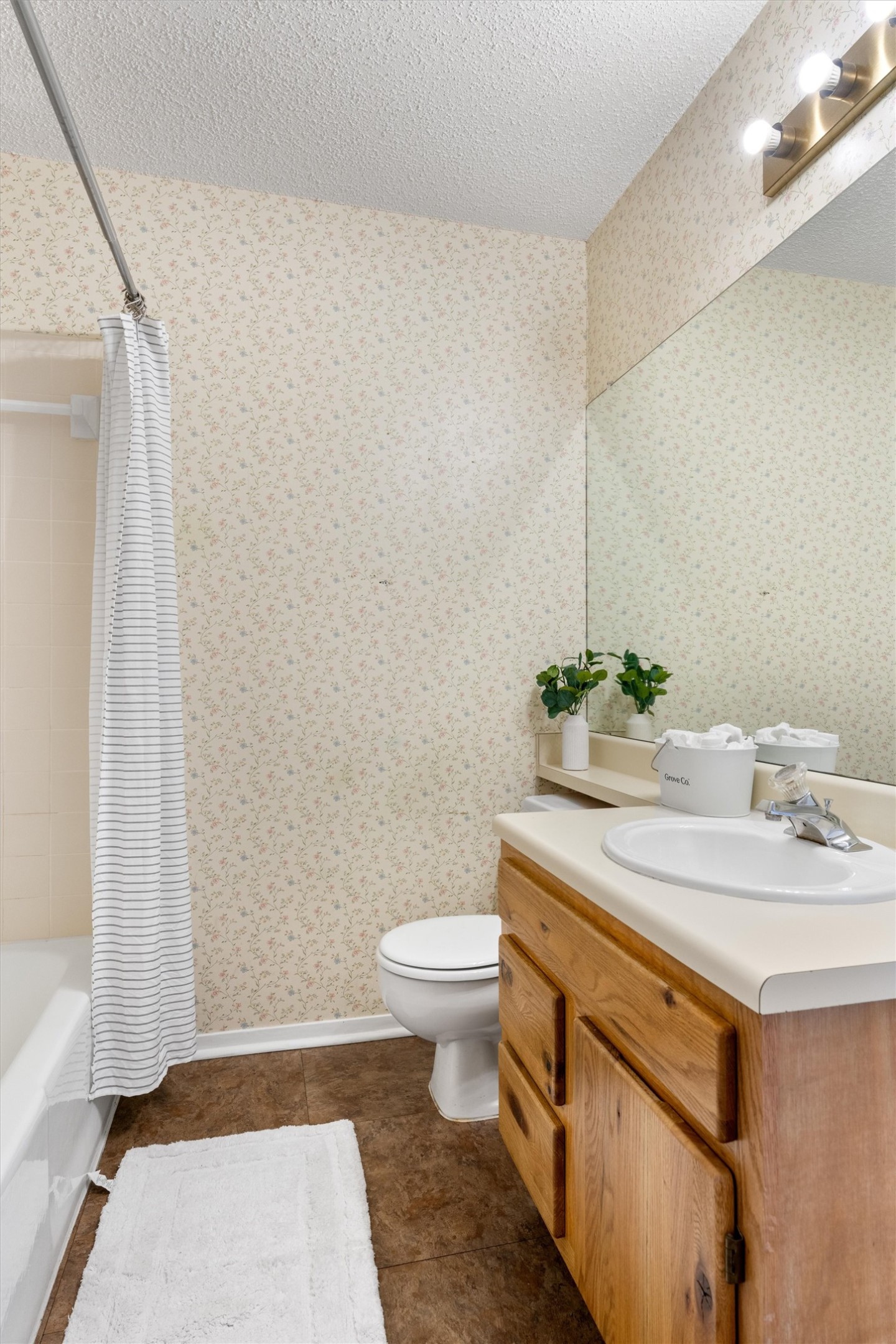 12314 Furrow Cove, Unit A Austin, TX 78753 - Photo 13 of 23 Bathroom featuring a textured ceiling, shower / bath combo with shower curtain, dark tile patterned floors, vanity, and wallpapered walls