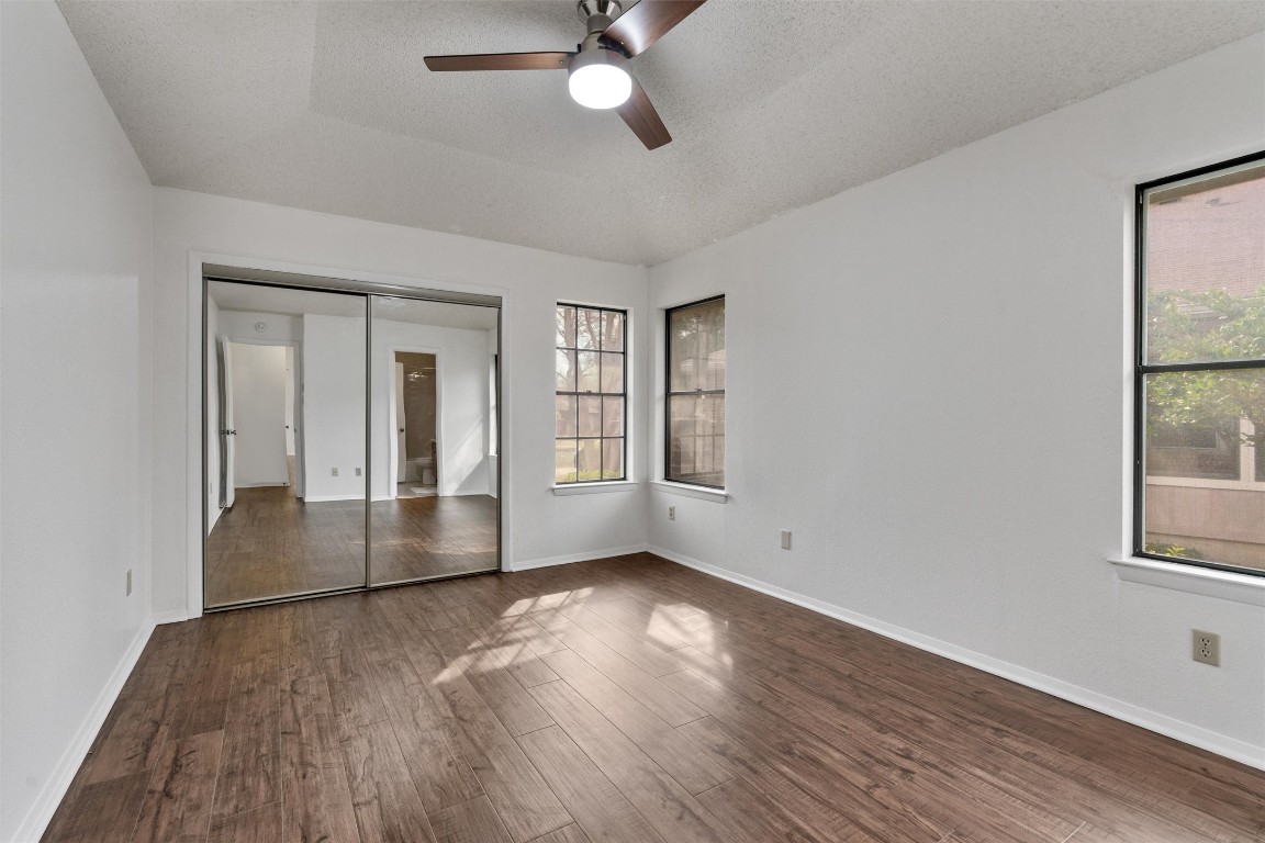 12314 Furrow Cove, Unit A Austin, TX 78753 - Photo 15 of 23 Unfurnished bedroom featuring dark wood-style flooring, ceiling fan, a textured ceiling, and a closet
