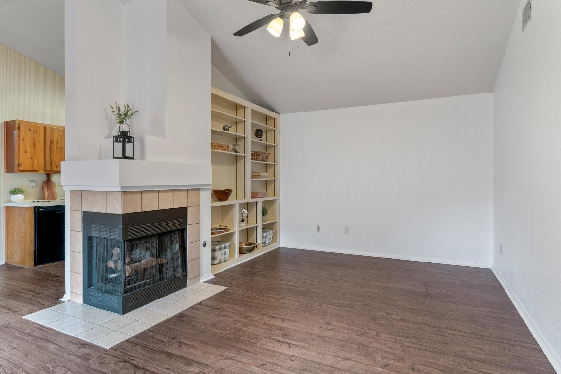 12314 Furrow Cove, Unit A Austin, TX 78753 - Photo 5 of 23 Living room featuring lofted ceiling, dark wood-style floors, a tiled fireplace, built in shelves, and a ceiling fan