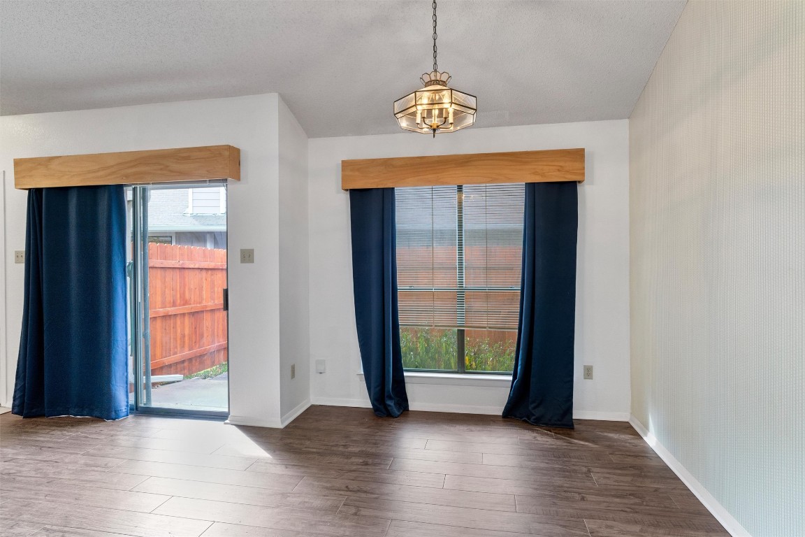 12314 Furrow Cove, Unit A Austin, TX 78753 - Photo 7 of 23 Empty room featuring wood finished floors and a chandelier