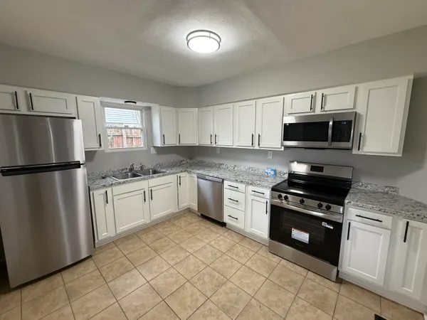 a kitchen with granite countertop a refrigerator stove and microwave