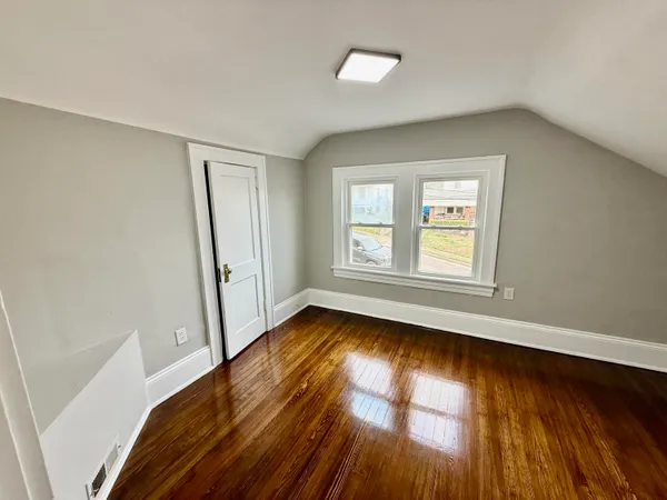 a view of an empty room with wooden floor and window
