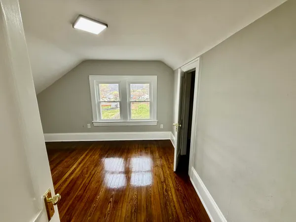 an empty room with wooden floor and entrance