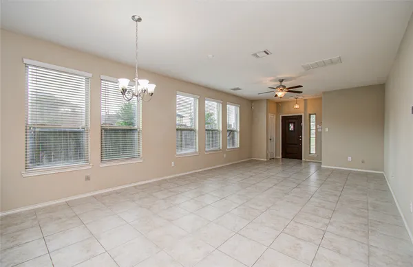 a view of an empty room with chandelier and window