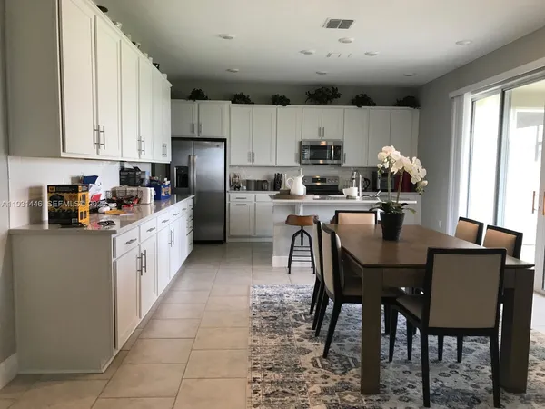 a kitchen with stainless steel appliances granite countertop a table chairs sink refrigerator and cabinets
