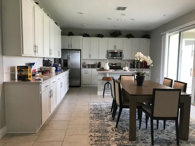 a kitchen with stainless steel appliances granite countertop a table chairs sink refrigerator and cabinets