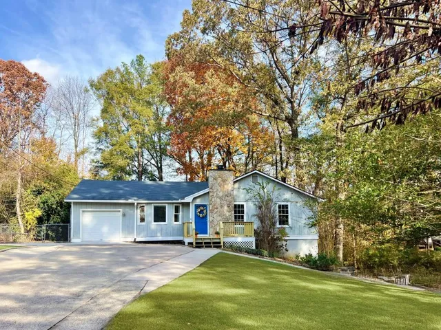 a front view of a house with a garden and trees