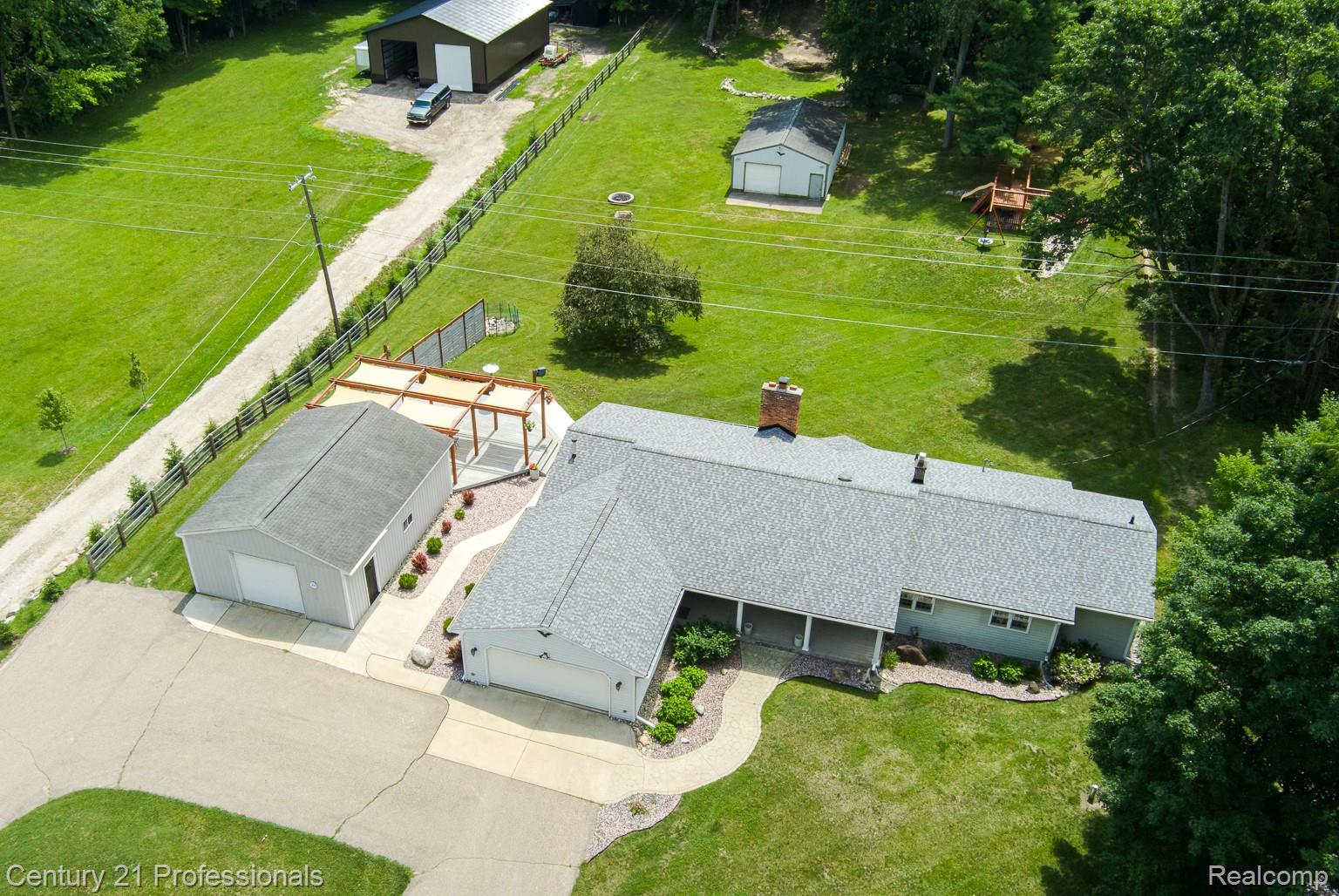 1790 Kent Road Ortonville, MI 48462 - Photo 4 of 64 Expansive property featuring a main residence with an attached garage, a detached garage, a large outbuilding, and a smaller shed, all surrounded by green space