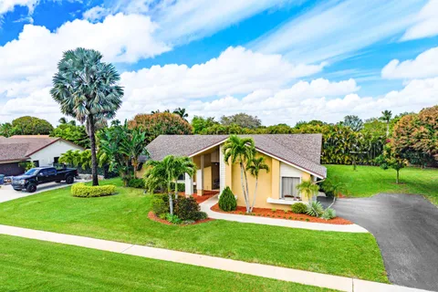 a view of a house with a big yard potted plants and large tree