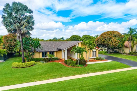 a front view of a house with garden and trees
