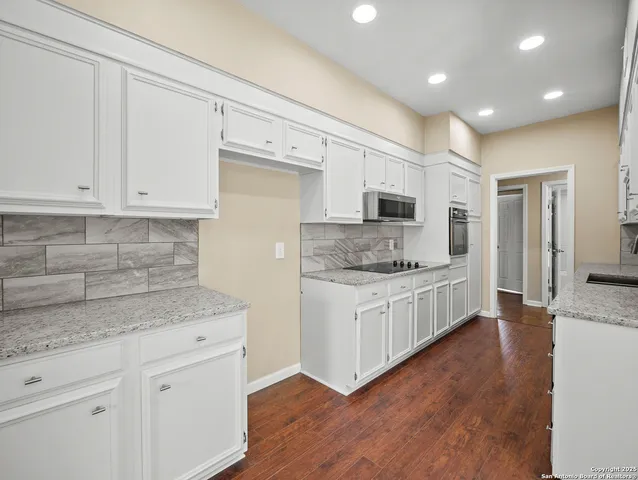 a kitchen with granite countertop white cabinets and white stainless steel appliances