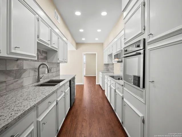 a kitchen with granite countertop a sink and wooden floor