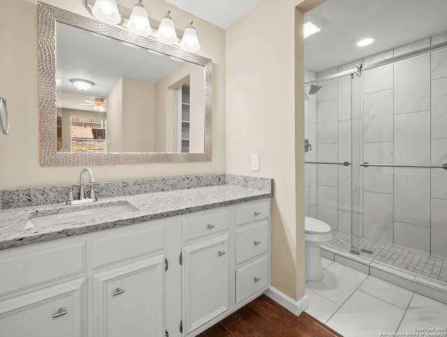 a bathroom with a granite countertop sink a toilet and a mirror