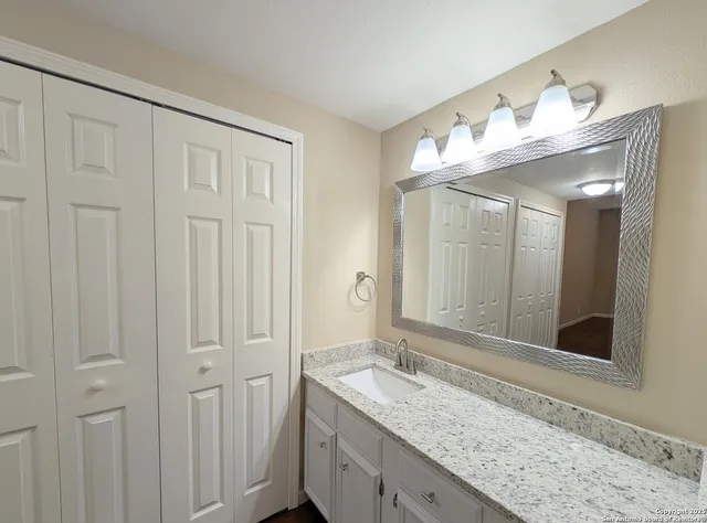 a bathroom with a granite countertop sink and a mirror