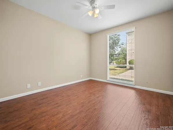a view of an empty room with wooden floor and a window