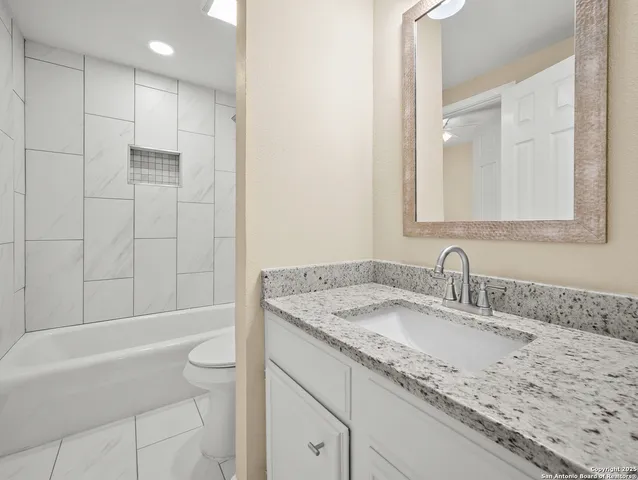 a bathroom with a granite countertop sink a toilet and bathtub