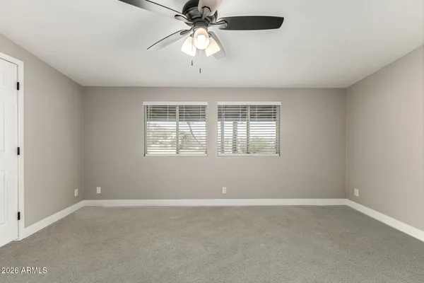 an empty room with a window and a fan