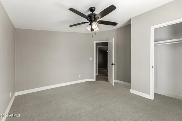 an empty room with closet and a ceiling fan