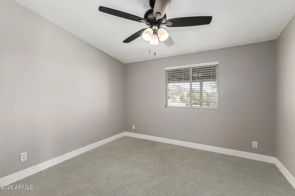 an empty room with a window and a fan