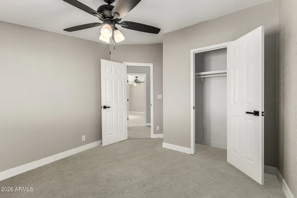 a view of an empty room and chandelier fan