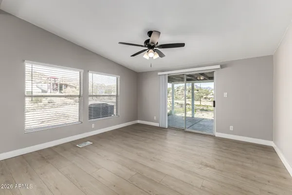 a view of empty room with wooden floor and fan
